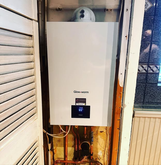 A boiler installed above pipework beside a window